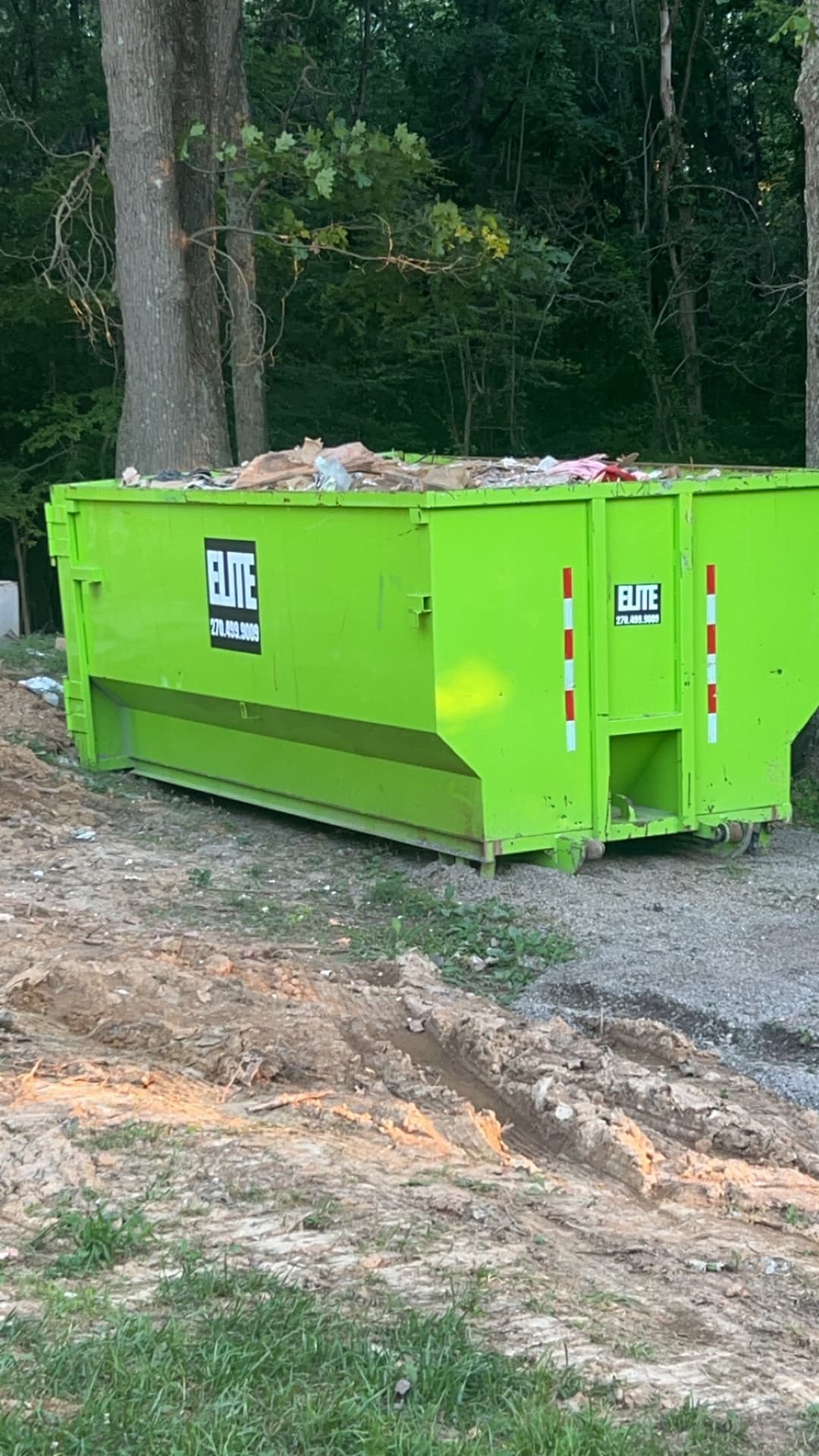 Elite Waste Service truck transporting multiple green dumpsters, showcasing our fleet and operations in Kentucky