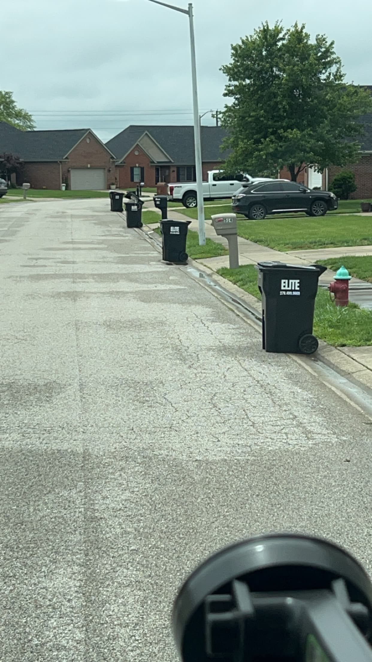 Elite Waste Services employee checking residential trash cart in front of house